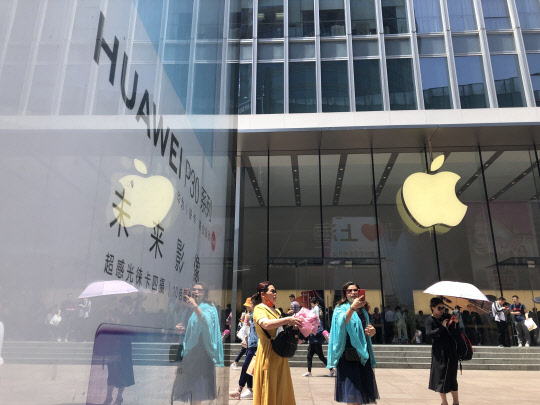 중국 상하이 난징둥루에 있는 애플 스토어 앞에 화웨이의 전략 스마트폰 P30 시리즈 광고물이 서 있다.  연합뉴스